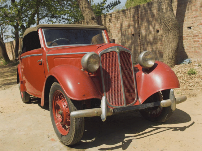 A red car on a dirt road
Description automatically generated